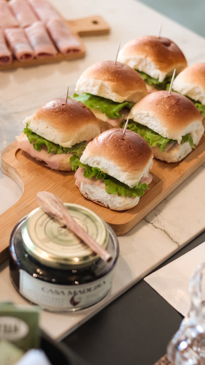 Delicious ham and lettuce sandwiches arranged neatly on a wooden serving board, ready for lunch.