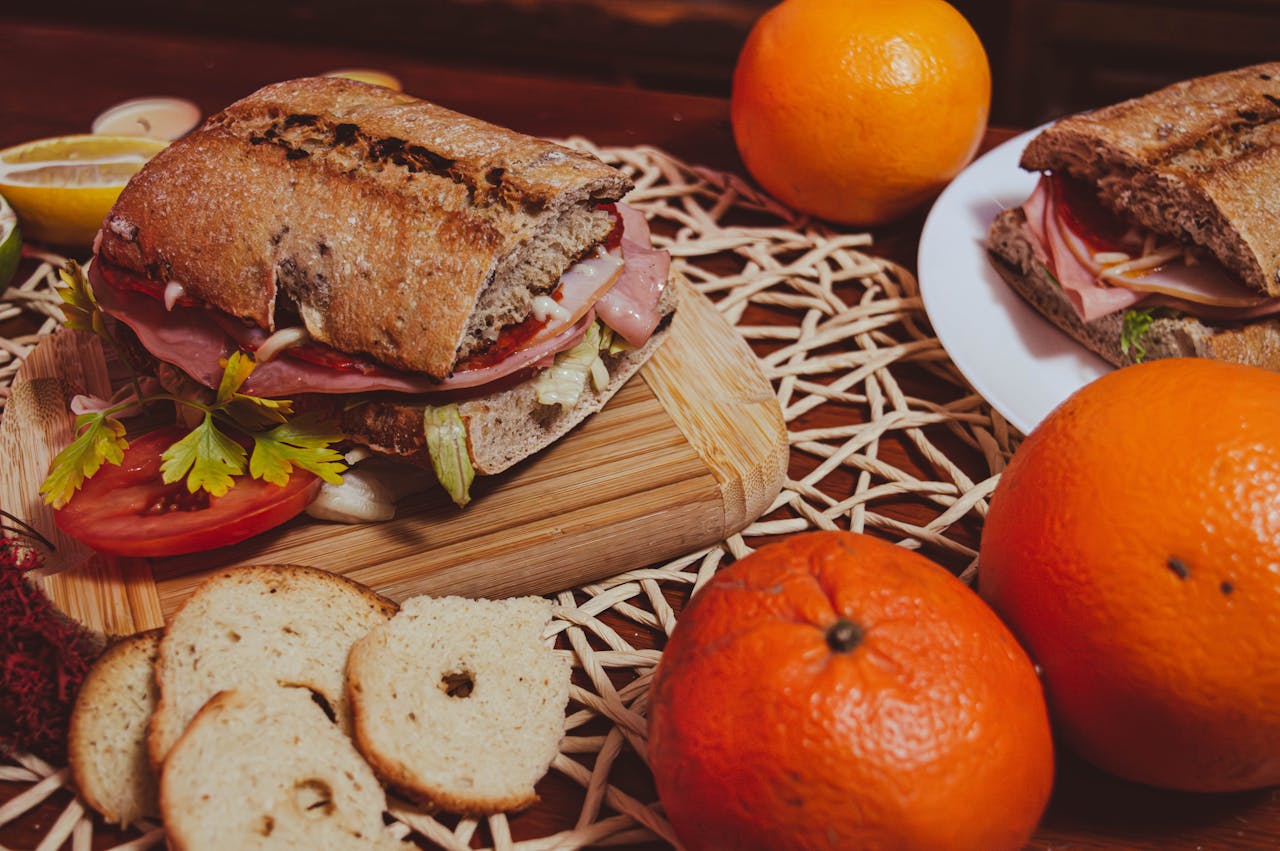 Delicious artisan sandwich with fresh oranges and sliced bread on a rustic woven mat in Brașov, Romania.