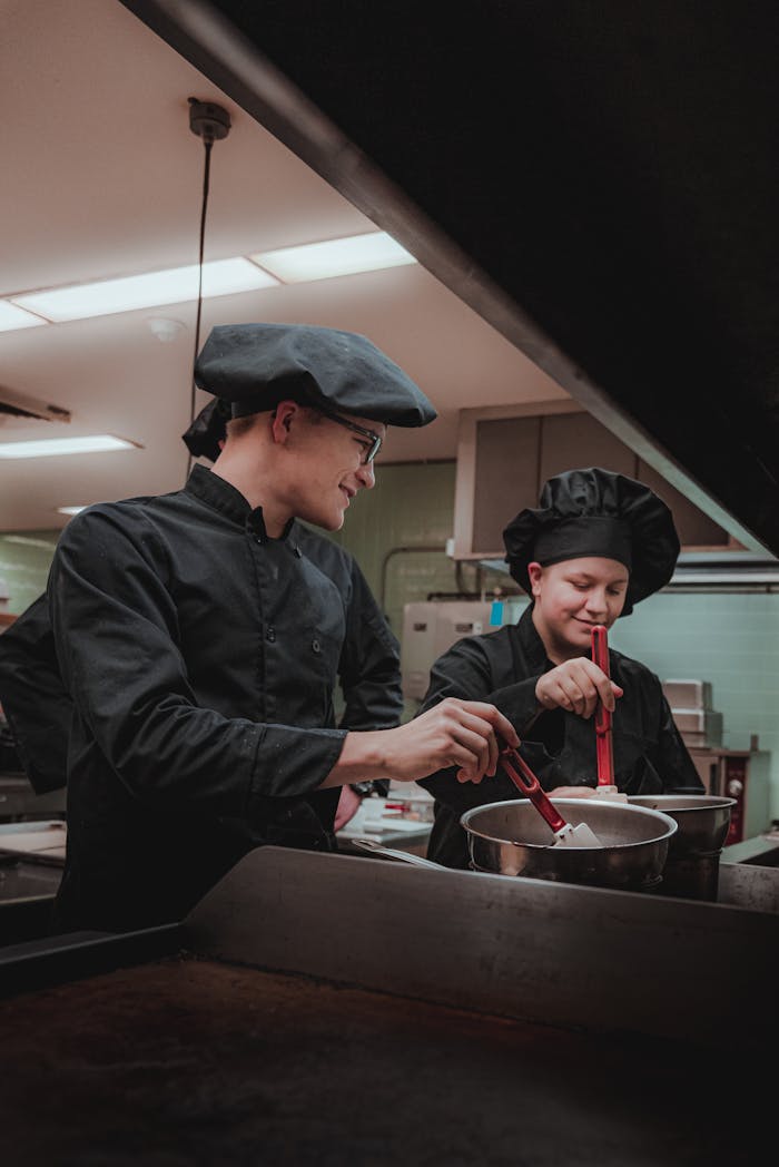 Two professional chefs cooking together, laughing and enjoying the culinary experience.