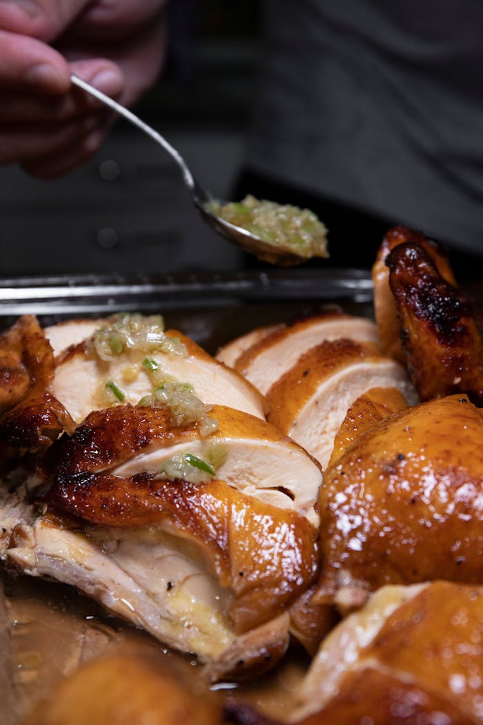 Sliced roasted chicken breast with garlic sauce, perfect for culinary enthusiasts.